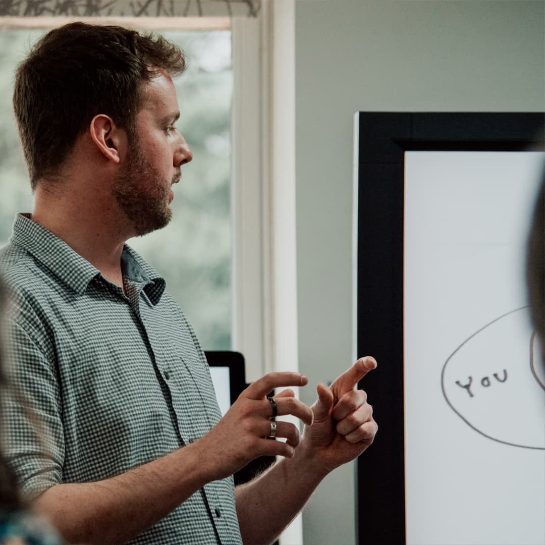 Nigel Fryatt wearing a white checked shirt looking at a presentation on a television